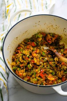 a pot filled with food sitting on top of a table next to a wooden spoon