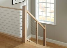 an empty room with white walls and wood floors, along with a wooden banister