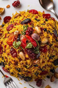 Saffron rice pilaf garnished with various dried fruits, nuts, and fresh herbs on a white plate, with cutlery on the side. Persian Basmati Rice, Persian Rice Recipe Basmati, Persian Food Iranian Cuisine, Persian Chicken, Christmas Rice, Rice Dishes Recipes, Rice Side Dish Recipes