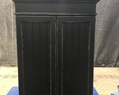 a tall black cabinet sitting on top of a blue mat