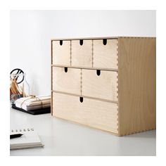 a wooden drawer sitting on top of a white table next to a pen and pencil holder