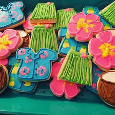 decorated cookies in the shape of clothes and flowers are displayed on a blue tablecloth