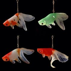 four different colored fish hanging from chains on a black background with the words monoio written below them