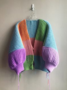 a colorful knitted sweater hanging on a hook