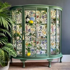 a green cabinet sitting next to a potted plant