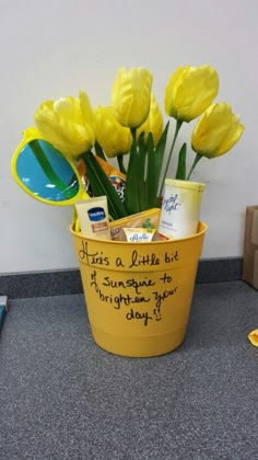 a bucket filled with yellow flowers on top of a counter next to a blue toothbrush