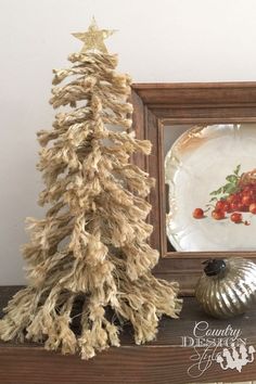 a small christmas tree sitting on top of a wooden shelf next to a plate and vase