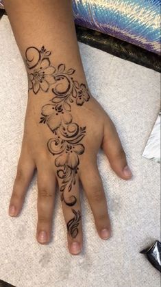 a woman's hand with a flower tattoo on it, sitting on top of a table