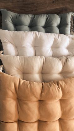 three pillows stacked on top of each other in different colors and sizes, sitting on the floor