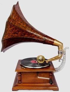 an old fashioned record player on top of a wooden stand with a brass plated horn