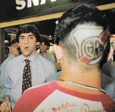 a group of men standing around each other in front of a small store with graffiti on their faces