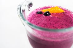 a close up of a smoothie in a glass with fruit on the top and garnish