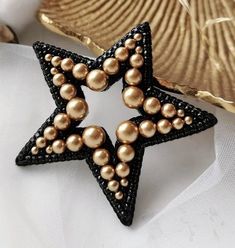 a black and gold star brooch sitting on top of a white napkin next to a seashell