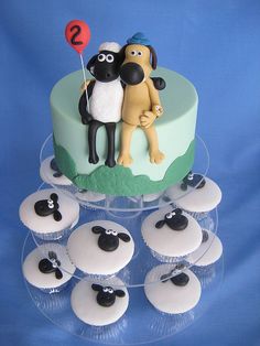 there is a cake with cupcakes on it and two sheep standing next to each other