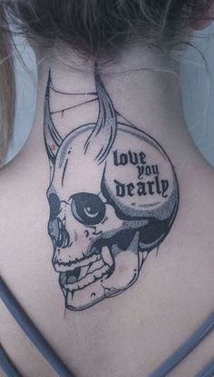 a woman's back neck with a skull and horns tattoo on her left side