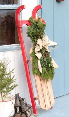 a wooden sled with christmas wreaths on it and a red pole holding the sleigh