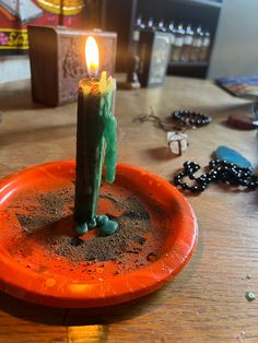 a lit candle sitting on top of a plate covered in dirt