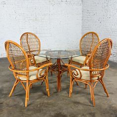 a round glass table with four chairs around it in front of a white brick wall