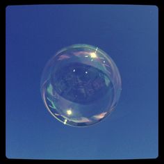 a clear bubble floating in the air on a sunny day with blue sky behind it