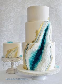 a three tiered cake with blue and white icing on it's side