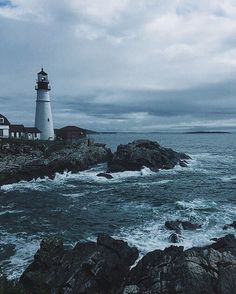 a light house sitting on top of a rocky cliff next to the ocean with waves crashing in front of it