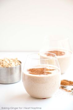 two glasses filled with food sitting on top of a white table next to a measuring cup