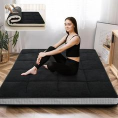 a woman sitting on top of a black mattress