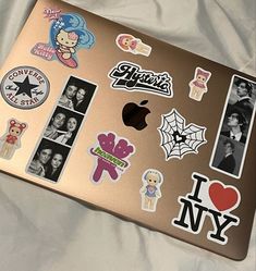 an apple laptop covered in stickers and pictures