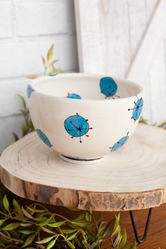 a white bowl with blue umbrellas on it sitting on top of a wooden stand