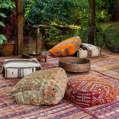 an outdoor area with various pillows and rugs