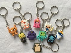 several different key chains with cartoon characters on them sitting on a white cloth covered surface