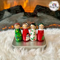 three little figurines sitting on top of a cell phone in front of a fireplace