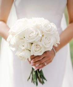 a bride holding a bouquet of white roses