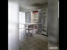 an empty room with a desk and chair in it, surrounded by shelving units