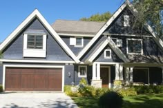 a blue house with white trim and brown garage doors