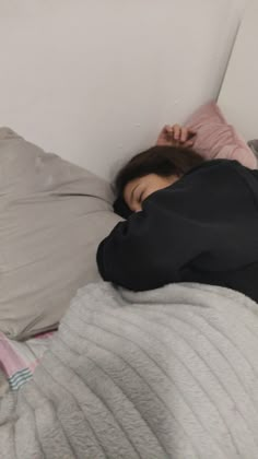 a woman laying in bed with her head on the pillow