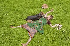 a woman laying in the grass with her dog and another dog lying on it's back