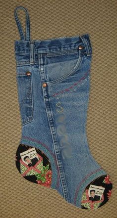 a pair of blue jeans with embroidered patches on the bottom and sides, hanging from a wall