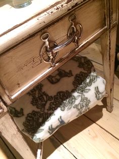 an upholstered chair sits in front of a wooden table with drawers on it