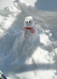 a snowman with a red bow sitting in the snow