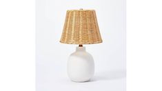 a white table lamp with a wicker shade on the base and a light bulb