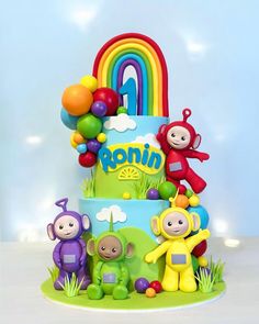 a birthday cake decorated with fondant characters and rainbows on it's side