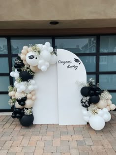 an arch decorated with black and white balloons