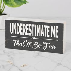 a wooden sign that says, underestimate me that'll be fun