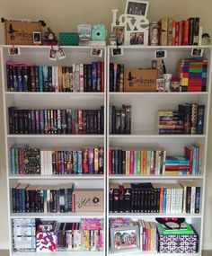 a book shelf filled with lots of books on top of white shelves next to a wall