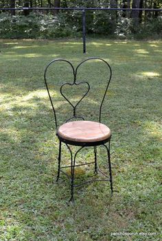 an iron chair with a heart shaped seat in the grass