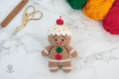 a crocheted teddy bear sitting next to some yarn and scissors on a table