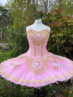 a pink and gold tutule dress sitting on top of a mannequin