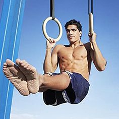 a shirtless man hanging upside down on a swing