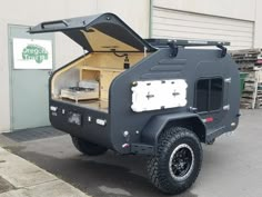 an off road camper is parked in front of a building with its doors open